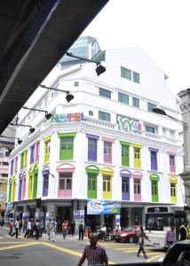 a white building with colorful windows on a city street at YY48 Hotel 2 Mins Walk From Masjid Jamek LRT Station in Kuala Lumpur