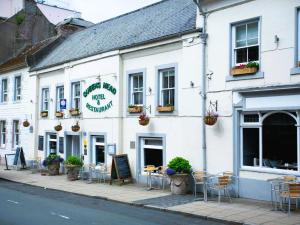 a white building with tables and chairs on a street at Queens Head Hotel in Berwick-Upon-Tweed