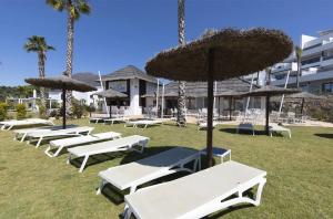 - une rangée de chaises longues et de parasols blancs dans l'établissement Penthouse in exclusive resort, à Estepona