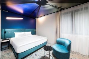 1 dormitorio con 1 cama y 1 silla azul en Three Corners Downtown Hotel en Budapest