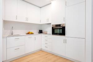 a white kitchen with white cabinets and a wooden floor at Genteel Home Aire in Seville