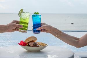 dwoje ludzi trzymających drinki i miskę jedzenia na stole w obiekcie Watermark Hotel & Resorts Okinawa Miyakojima w mieście Miyako-jima