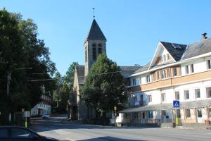 uma igreja com uma torre numa rua ao lado de um edifício em Au lit de l'Amblève em Malmedy