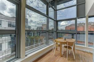 uma mesa e cadeiras num quarto com janelas grandes em * Stunning City Centre Penthouse Over Two Floors * em Manchester