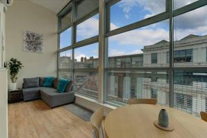 uma sala de estar com uma mesa e uma grande janela em * Stunning City Centre Penthouse Over Two Floors * em Manchester