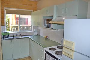a kitchen with white cabinets and a white refrigerator at Wards Holiday Flat 3 in South West Rocks