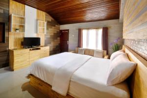 a bedroom with a large white bed and a television at Jero Delod Guesthouse in Tabanan