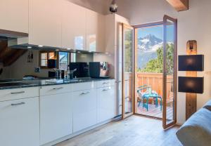 a kitchen with white cabinets and a view of a mountain at Panoramapark Soleil Chalet E in Wengen