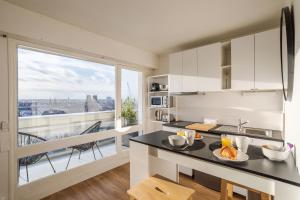 une cuisine avec un comptoir et une grande fenêtre dans l'établissement BALCON DU CANAL - Studio lumineux avec balcon au bord de la Vilaine et de lhyper centre-ville, à Rennes