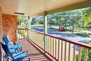 two blue chairs on a porch with a view of a street at Parkview Lodge - Bring your own linen. in South West Rocks