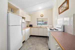 a kitchen with white appliances and a white refrigerator at PJ's Cottage - Bring your own linen. in South West Rocks +5 photos