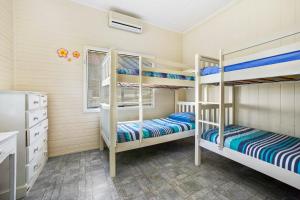 a bedroom with three bunk beds in a room at PJ's Cottage - Bring your own linen. in South West Rocks