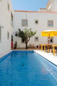 een zwembad met een tafel en een parasol bij PTM DownTown Hostel&Suites in Portimão