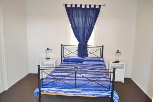 a bedroom with a bed with a blue curtain at Rockleigh in South West Rocks