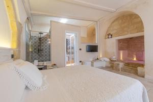 a bedroom with a large white bed and a bathroom at Masseria dei Monaci in Otranto