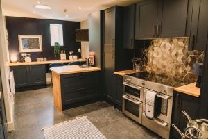 a kitchen with black cabinets and a stove at Maes Yr Haf in Swansea