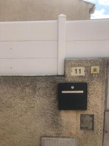 ein Schild an der Seite eines Gebäudes mit einer Uhr in der Unterkunft Les Amandiers in Abeilhan