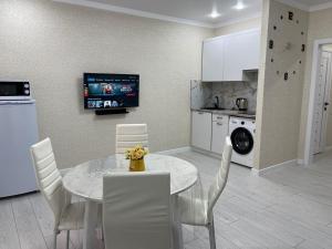a kitchen and dining room with a table and chairs at АУЕЗОВА 189б ЖК Салтанат Центр Евродвушка с 2 х спальной кроватью и двумя диванами in Kokshetau
