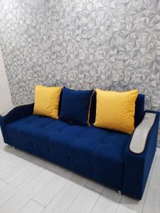 a blue couch with two yellow pillows on it at АУЕЗОВА 189б ЖК Салтанат Центр Евродвушка с 2 х спальной кроватью и двумя диванами in Kokshetau