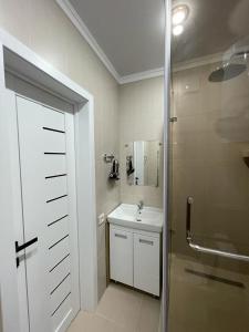 a white bathroom with a sink and a shower at АУЕЗОВА 189б ЖК Салтанат Центр Евродвушка с 2 х спальной кроватью и двумя диванами in Kokshetau