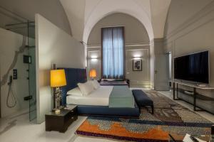 a bedroom with a bed and a flat screen tv at La Fiermontina Palazzo Bozzi Corso Hotel in Lecce