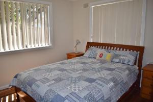 a bedroom with a bed with a blue and white quilt at Mariner 16 Flat 1 South West Rocks in South West Rocks