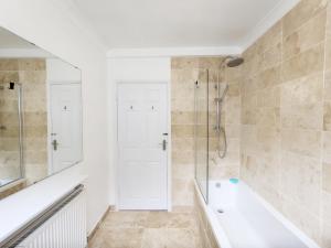 a white bathroom with a shower and a bath tub at Coastal - Wittering in West Wittering +32 photos