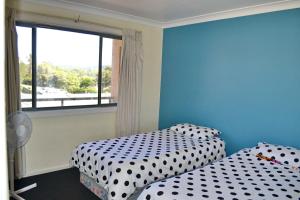two beds in a room with a window at Northpoint Apartment 5 in South West Rocks