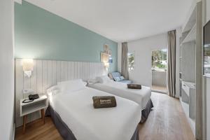um quarto de hotel com duas camas e uma varanda em Barceló Aguamarina em Cala d´Or