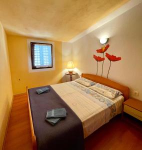 a bedroom with a bed with red flowers on the wall at Apartments Dražica 4 in Zubovići