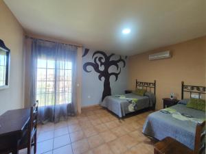 a bedroom with two beds and a tree mural on the wall at POSADA LOS PEDREGALES in El Granado