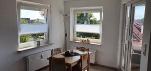a dining room with three windows and a table and chairs at Ferienwohnung Strandjuwel am Strand in Norddeich