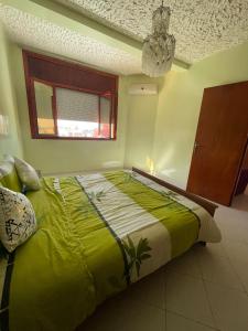 a bedroom with a large green bed with a window at Mehdia Ville in Plage de Mehdia