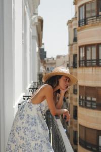 a woman wearing a straw hat standing on a balcony at Helen Berger Boutique Hotel in Valencia