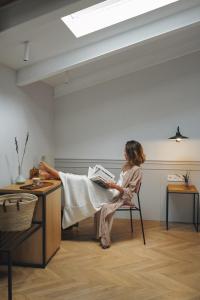 a woman sitting in a chair reading a book at Helen Berger Boutique Hotel in Valencia