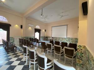 une chambre avec une table, des chaises et un écran de projection dans l'établissement Vivaana, à Mandāwa