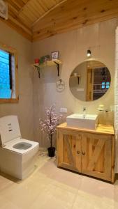 ein Badezimmer mit einem WC, einem Waschbecken und einem Spiegel in der Unterkunft Bombay Camping Company in Lonavla