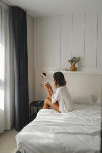 a woman sitting on a bed looking at her phone at Ramirez Flats Valencia in Valencia