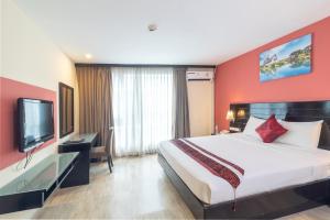 um quarto de hotel com uma cama grande e uma televisão de ecrã plano em Boss Suites Nana Hotel em Bangkok