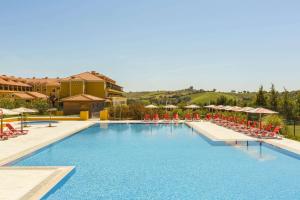 a large swimming pool with red chairs and tables at Dolce CampoReal Lisboa in Turcifal