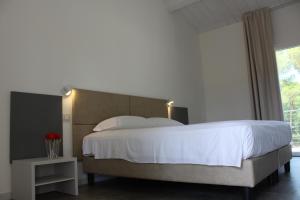 a bedroom with a large white bed and a window at Tennis Rocchette Resort in Castiglione della Pescaia