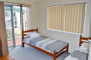 a bedroom with two beds and a balcony at Spencers Cottage in South West Rocks