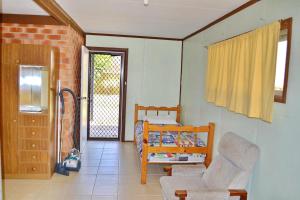 a room with a bedroom with a bed and a chair at Spencers Cottage in South West Rocks