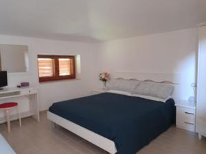 a white bedroom with a blue bed and a desk at La Quercia in Altavilla Silentina