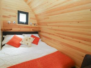 Cama en habitación pequeña con paredes de madera en Sunset Pod, en Shrewsbury