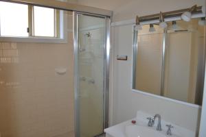 Un baño con ducha, lavabo y espejo. en Clarkes Flat 1, en South West Rocks
