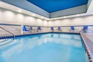 - une piscine avec des chaises bleues dans un bâtiment dans l'établissement La Quinta Inn & Suites by Wyndham South Bend near Notre Dame, à South Bend