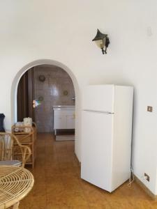 Il comprend une cuisine équipée d'un réfrigérateur blanc et d'une table. dans l'établissement Casa Trullo Sole, à Cisternino