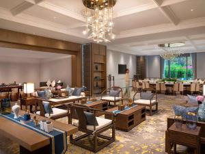 Pullman Yuxi في Yuxi: لوبي الفندق به طاولات وكراسي وثريا