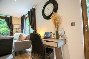 a room with a desk and a clock on the wall at Campbell Park Apartment - City Centre - Free Parking, Balcony, Super-Fast Wifi and Smart TV with Netflix by Yoko Property in Milton Keynes